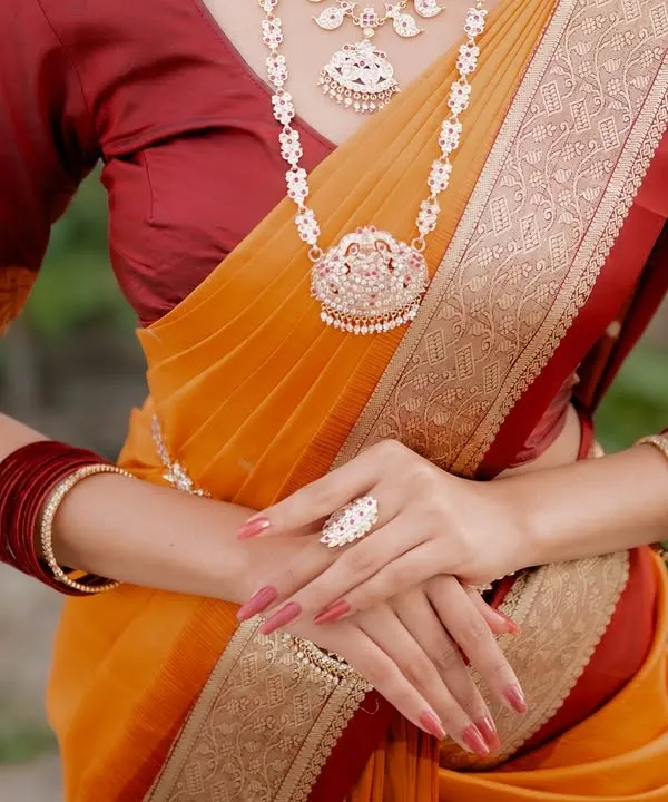 A close-up shot focusing on the hands, jewelry, and waist of a model in a traditional saree. This composition highlights the ring, bangles, and the saree's border, perfect for showcasing a complete ethnic look.