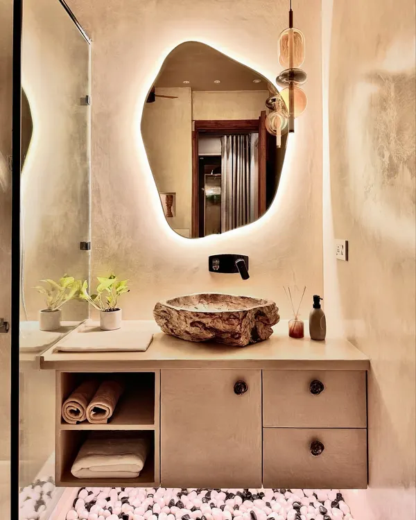 This bathroom is my idea of a personal sanctuary. I used a custom-shaped, backlit mirror to create a soft glow against the lime-washed walls, which have a beautiful, chalky texture. The sink is carved from a single piece of natural stone, making it a functional sculpture. It’s a perfect example of my spa-style bathroom renovation work, where I bring in organic forms and earthy materials to create a sense of calm.