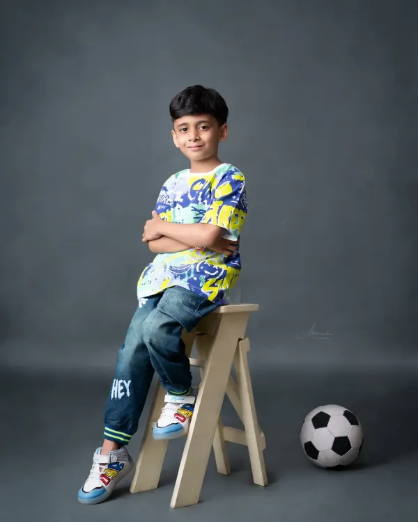 A cool and casual portrait of a 7-year-old boy, showing off his sporty side with a soccer ball.