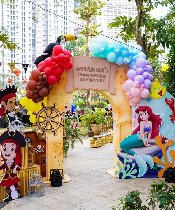 A spectacular outdoor entrance for a 'Mermaids vs. Pirates' party, perfectly blending the two themes with character cutouts and balloon arches.