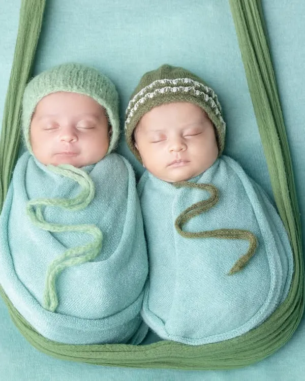 Born together, best friends forever. This hanging sling pose is perfect for showcasing newborn twins, keeping them snug and close just like they were in the womb.