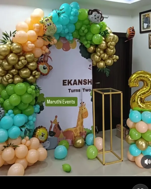 A beautiful jungle-themed party with modern, retro-colored balloons. The organic arch in shades of green, gold, and peach is paired with a cute animal backdrop and a gold stand.