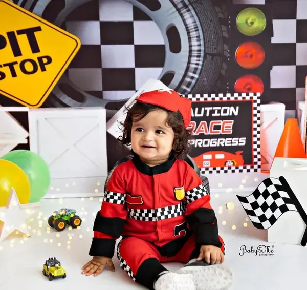 This little racer is all smiles and ready for his first birthday pit stop. The detailed race car set, complete with a Lightning McQueen cutout, is perfect for capturing high-energy portraits.