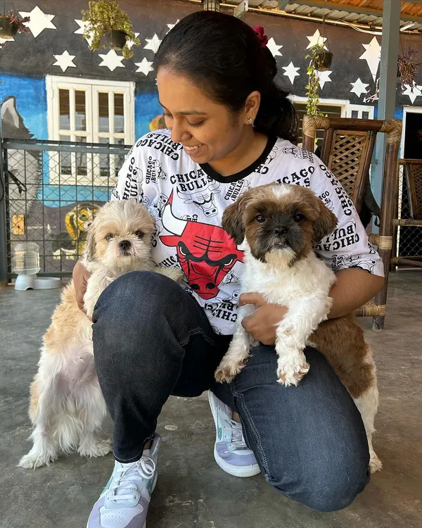 A visitor celebrating her dog's birthday, holding two adorable Shih Tzus.