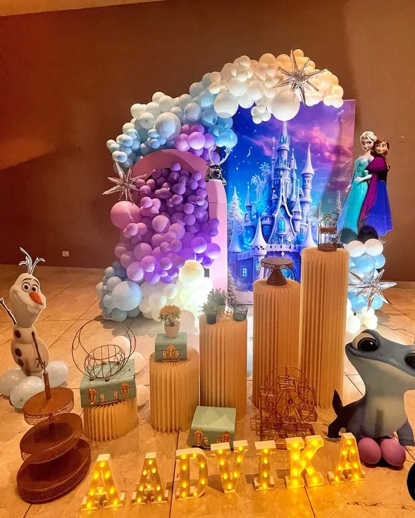 A complete Frozen-themed birthday party setup. I use custom printed backdrops, character cutouts like Elsa and Anna, and themed props to create an immersive world. The balloon garland in shades of blue, purple, and white mimics a winter sky, complete with starburst accents.