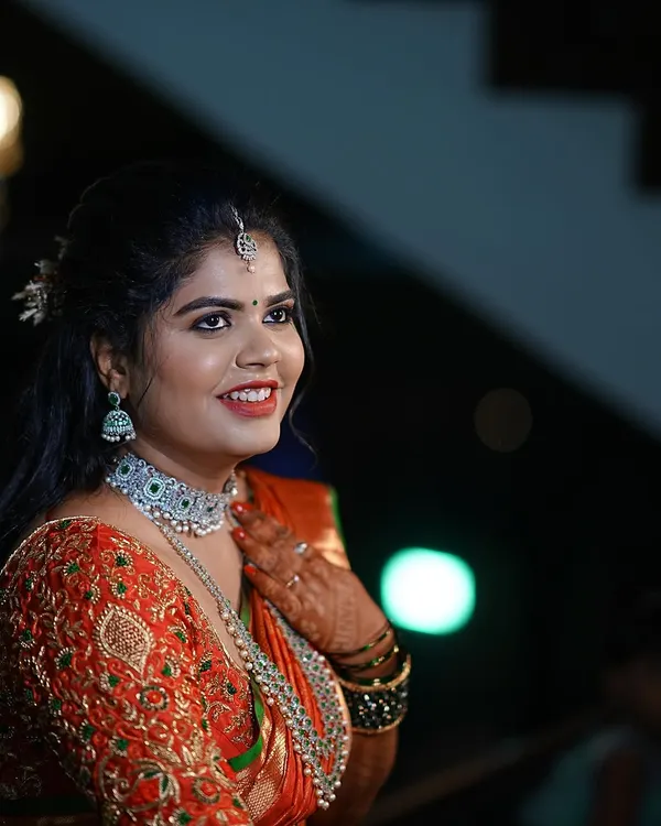 A radiant bride on her wedding day. I designed this heavily embroidered orange and green blouse to perfectly complement her rich silk saree.