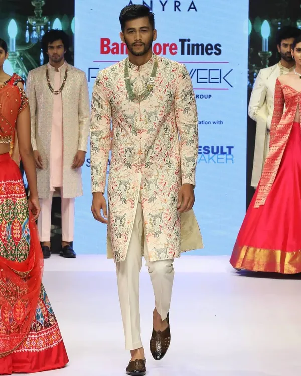 A model walks the runway at Bangalore Times Fashion Week in one of my creations. This light pink sherwani is fully embroidered with a multi-color pattern, showcasing my commitment to detailed, artistic craftsmanship.