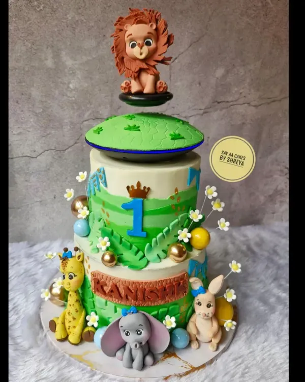 This two-tier jungle adventure cake was for a wild first birthday. It features a floating top tier and adorable, handmade fondant animals like a giraffe, elephant, and lion, creating a playful safari scene.