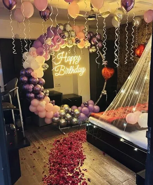 This is the kind of birthday surprise I love to create. I can transform the room with a neon sign, a beautiful balloon arch, a path of rose petals, and a fairy-light cabana bed to make your partner's day truly unforgettable.