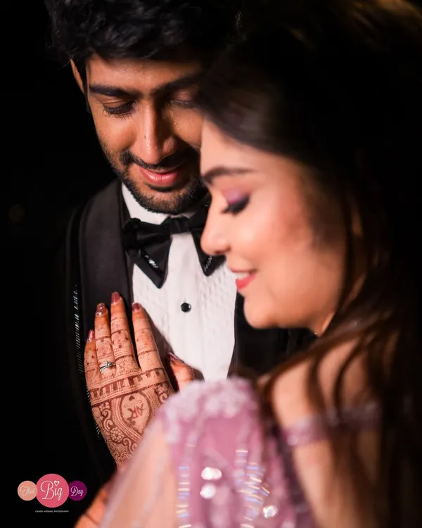 An intimate close-up under dramatic lighting. We focus on the details, from the henna on her hand to the adoration in his eyes.