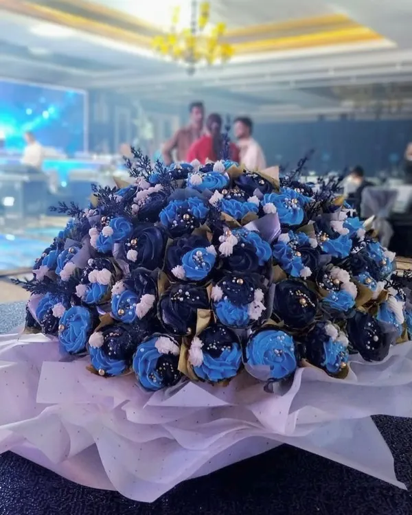 A massive 100-cupcake bouquet created for a corporate event. The cupcakes are decorated in shades of blue and white, creating a stunning and delicious centerpiece.
