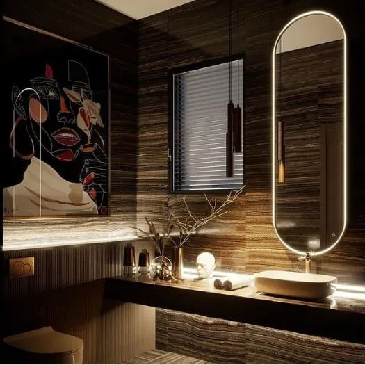 I designed this powder room to feel like a private, moody retreat. The space is defined by dark, book-matched marble walls, minimalist pendant lighting, and a custom backlit mirror that provides a soft glow. The modern art piece adds a bold, personal touch to this luxury washroom design.