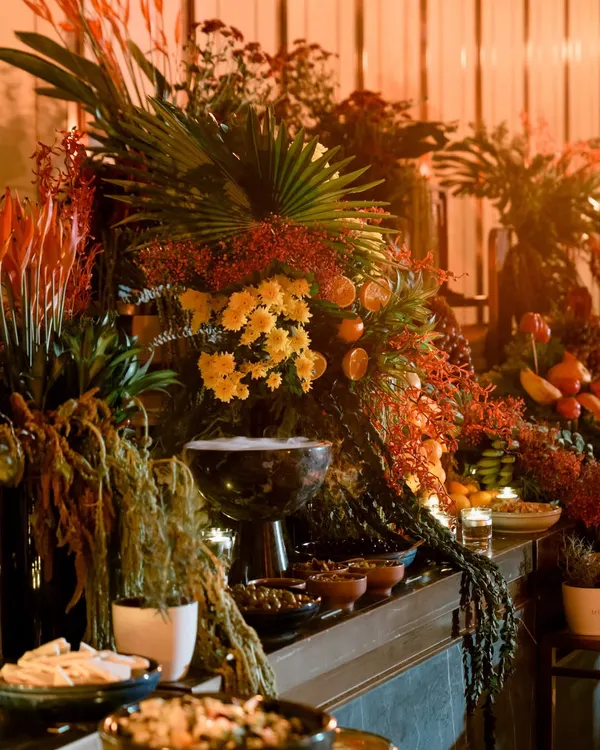 The goal is to create a scene of overwhelming beauty. This section of the grazing table shows how I use large palm fronds and dense floral arrangements to build height and drama, making the food display feel like a lush, tropical oasis.