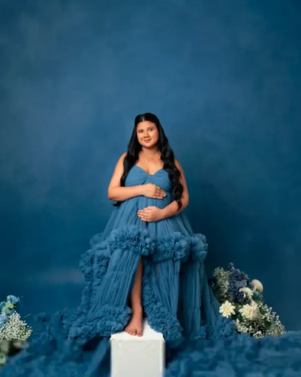 A solo portrait showcasing the grandeur of our blue ruffled tulle gown. The cascading fabric creates a stunning visual, perfect for a regal and memorable maternity photo.