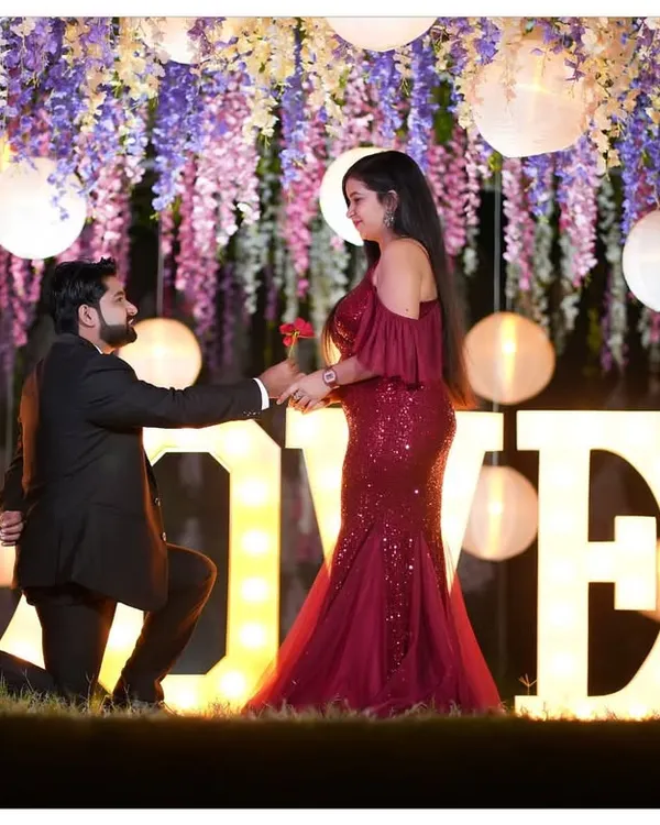 A picture perfect proposal moment for a pre-wedding shoot, captured using our illuminated 'LOVE' sign and floral decor. This setup is ideal for creating romantic and memorable evening shots.
