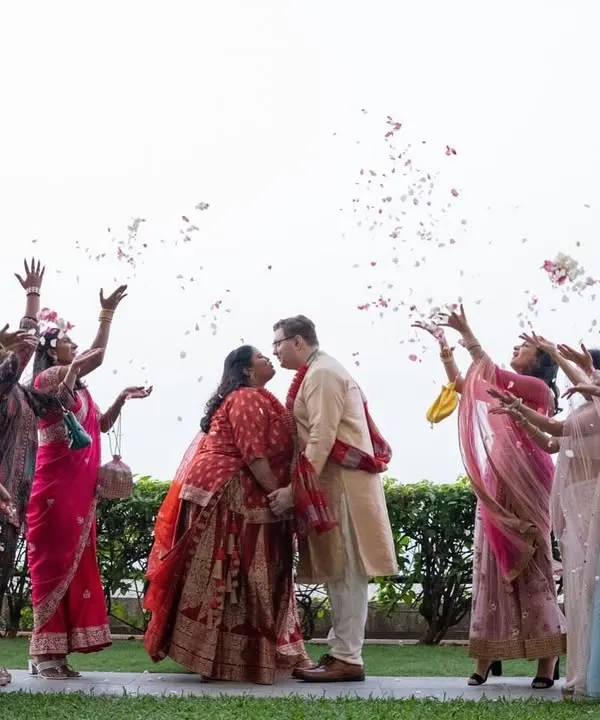 A beautiful moment from a multicultural wedding in Mumbai, where guests from different backgrounds shower the couple with flower petals.