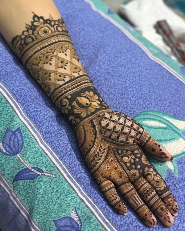 A complete view of an intricate, full-coverage henna design. This style features a heavy cuff, a central mandala on the palm, and detailed work on every finger.