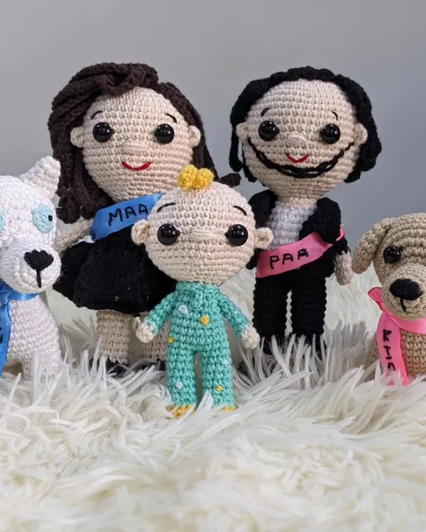 A custom crochet family portrait created as a special baby shower gift. It features the mom-to-be, dad, a new baby, and their two beloved dogs, each with a personalized sash.