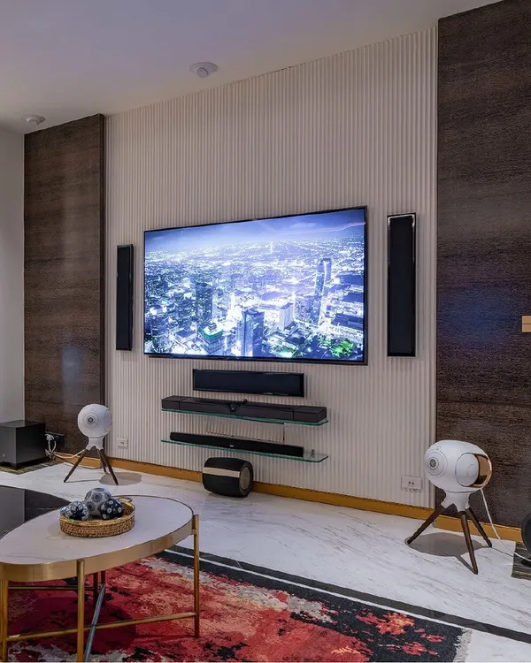This is what we mean by lifestyle technology. This living space features a fully integrated audio-visual system, including a large 4K display, multiple soundbars, tower speakers, and a pair of iconic Devialet Phantom wireless speakers. It's a perfect example of how we combine high performance with luxury interior design.