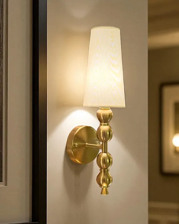 The Luminique Spire Wall Light is a classic choice for adding a focused glow. Its beaded column and simple tapered shade make it ideal for placing on either side of a bed, a mirror, or a piece of art.