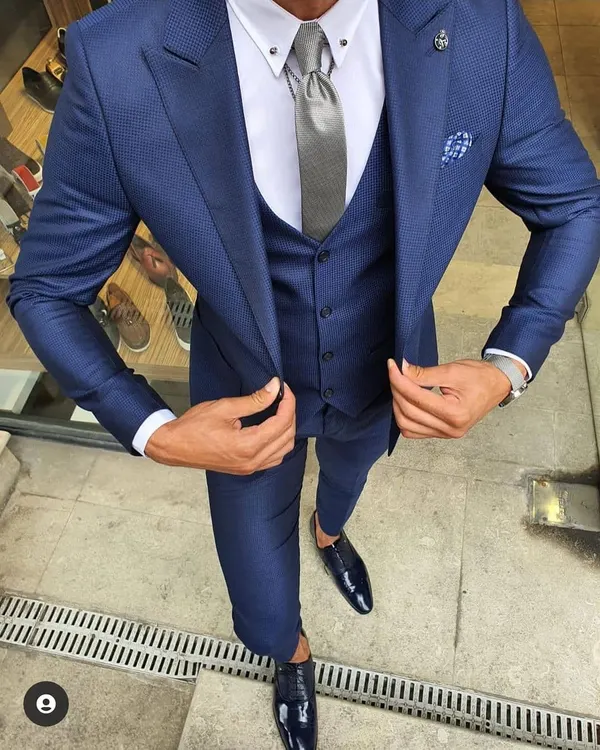 A perfectly tailored three piece suit is a must have for any man's wardrobe. This slim fit navy blue suit, shown here with a matching waistcoat and a crisp white shirt, is ideal for business meetings, weddings, or any formal event where you need to look your best.