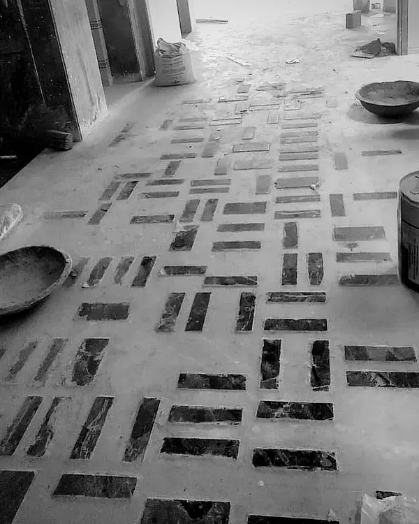 A modern geometric pattern being laid on the floor of a project in Delhi. We used pieces of dark stone set into the concrete to create this custom design.