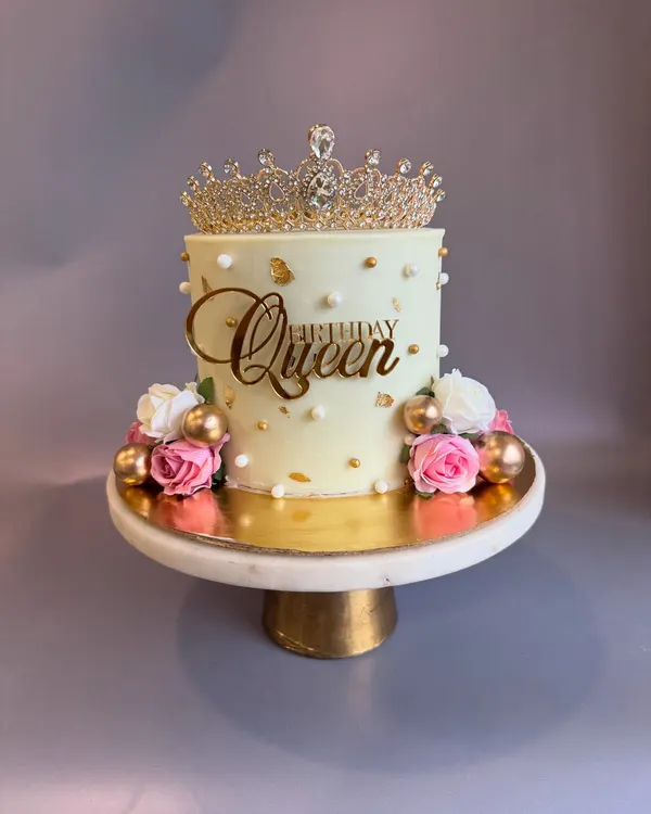 A cake that screams elegance and royalty, fit for a queen on her 40th birthday. This design features a beautiful crown topper, gold accents, and delicate roses.