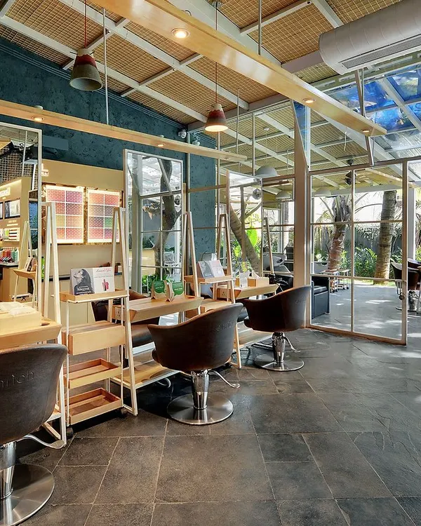 The Enrich Salon in Bangalore is a space designed to be surrounded by nature. We preserved an old bungalow and its verdant vegetation, creating a salon with therapeutic vibes. This styling area features an open, airy design with views of the lush garden.