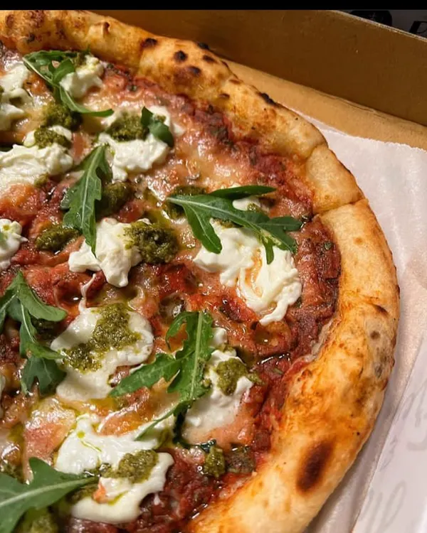 A beautiful close-up of my Pesto Burrata pizza. The combination of creamy burrata cheese, fresh pesto, and peppery arugula on our signature crust is simply divine.