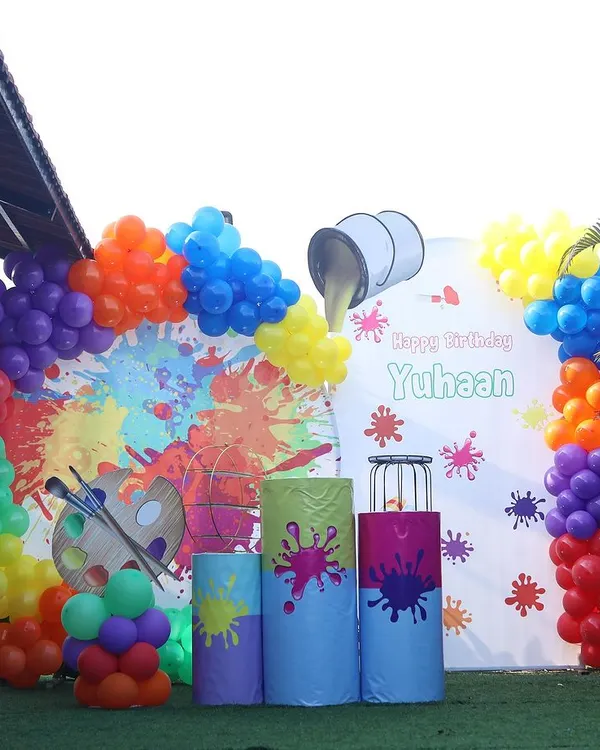 A vibrant and creative art-themed birthday party. This outdoor setup features a paint splatter backdrop and a rainbow of balloon colors, perfect for a budding artist.