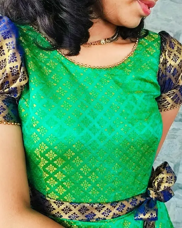 Here is a close-up of the 'Neelam' dress, custom-made from a client's saree. You can see the beautiful detail of the green and gold brocade fabric, the contrasting blue puff sleeves, and the delicate beadwork along the neckline.