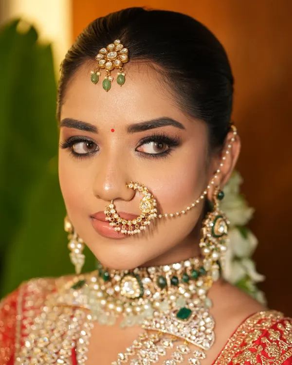 A close-up of the quintessential Indian bride. The sleek center-parted bun provides a perfect base for the maang tikka and nath, creating a clean, royal profile for the wedding ceremony.
