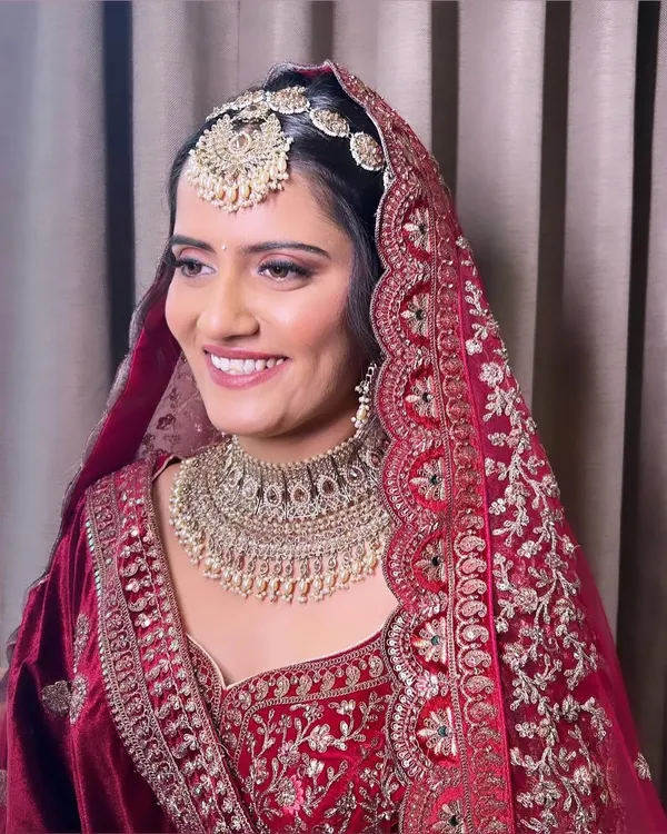 My beautiful bride ready for her Phera ceremony. She is wearing a traditional red velvet lehenga, and I created a classic bridal look with soft pink eyeshadow and a radiant base to match.