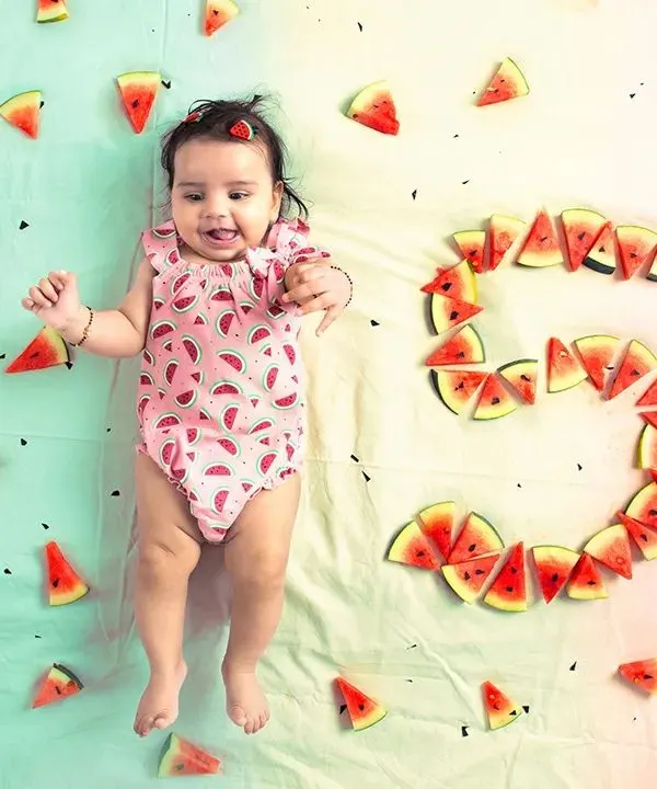 An adorable overhead shot from a baby milestone session, where a five-month-old is surrounded by watermelon slices arranged to form the number five. This highlights my creative and fun approach to baby photography.