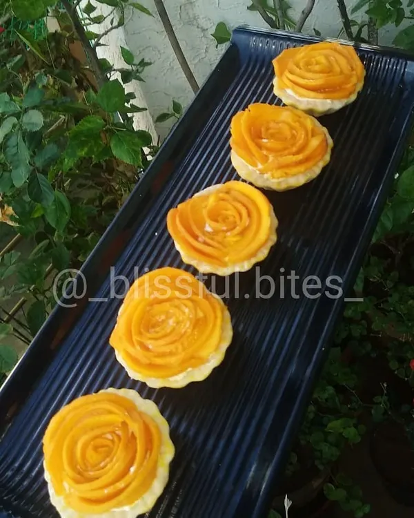 A tray of my beautiful Mango Rose Tartlets, a perfect dessert for the summer season. The fresh mango is sliced thinly and arranged to look like a rose on a creamy base.