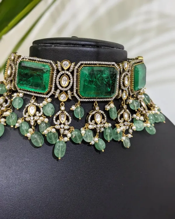 A stunning Victorian choker adorned with large emerald-colored stones and delicate strawberry beads. This is a statement piece that exudes luxury and is perfect for a grand reception.