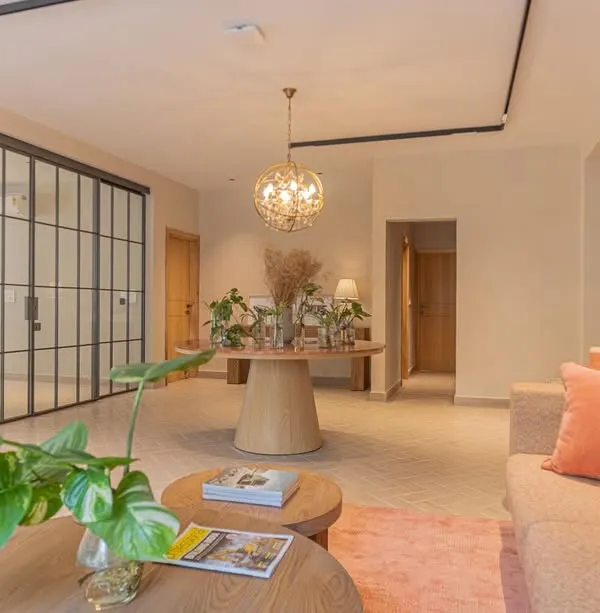 The waiting lounge of this office is designed to feel calm and welcoming. We used a soft, earthy color palette with pops of coral, natural wood furniture, and plenty of indoor plants. A crittall glass partition separates the lounge from a meeting room, maintaining an open and airy feel while providing acoustic privacy.