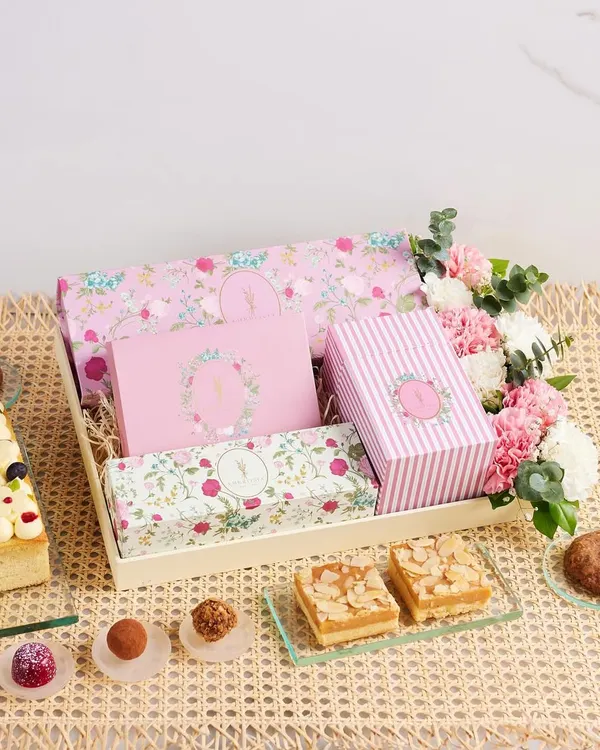 A glimpse into our thoughtfully crafted dessert hampers, where every detail is designed to bring joy. This beautiful arrangement features a mix of our signature bakes, Belgian truffles, and almond bars, all nestled with fresh flowers.