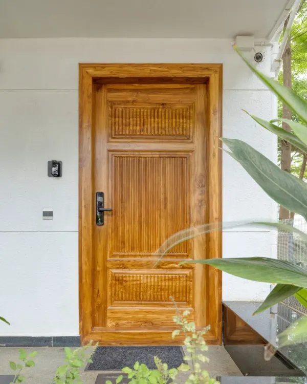 The main door at Villa 17, crafted from solid teak with carved details. It offers a warm and impressive welcome.