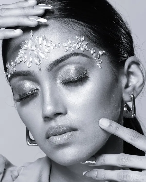 A stunning black and white beauty portrait focusing on a crystal headpiece and shimmering eyeshadow. The monochrome style enhances the texture and sparkle.