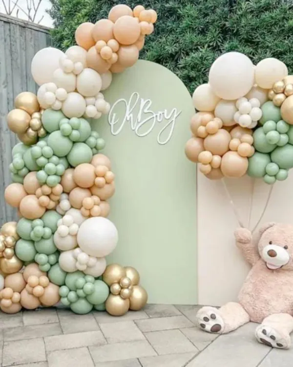 A stylish and modern "Oh Boy" baby shower setup, perfect for an outdoor or indoor event. This design features an organic balloon garland in a sophisticated palette of sage green, beige, and gold, set against an arched backdrop with custom lettering and a large teddy bear prop.