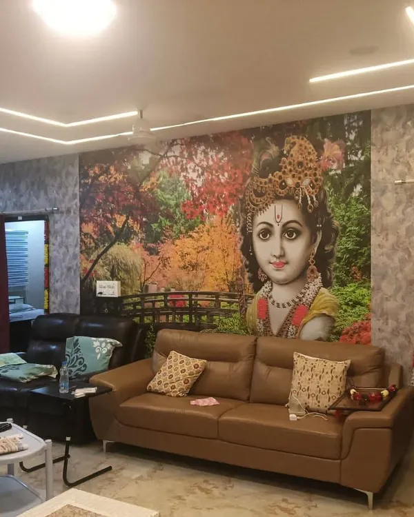 A large, colorful mural of Lord Krishna as a child, creating a vibrant and divine focal point in this living room.