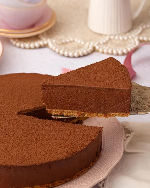 A perfect slice of my Belgian Chocolate Mousse Cake being lifted, showcasing its incredibly smooth and velvety texture against the crisp biscuit base.