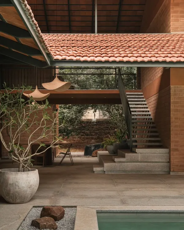 This courtyard at Villa Maati captures our design philosophy. We used natural materials like brick and Mangalore tiles to create a seamless flow between the indoor living spaces, the staircase, and the outdoor pool area, embracing true indoor-outdoor living.