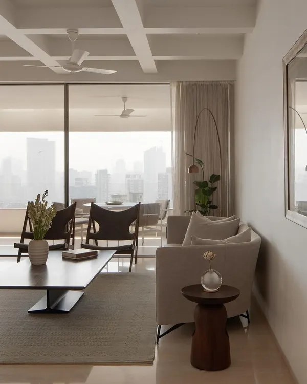 This view of the Altamount Road apartment showcases several bespoke furniture pieces, including the dark wood coffee table and sculpted side table. Each item was designed to complement the light-filled, open-plan living space.