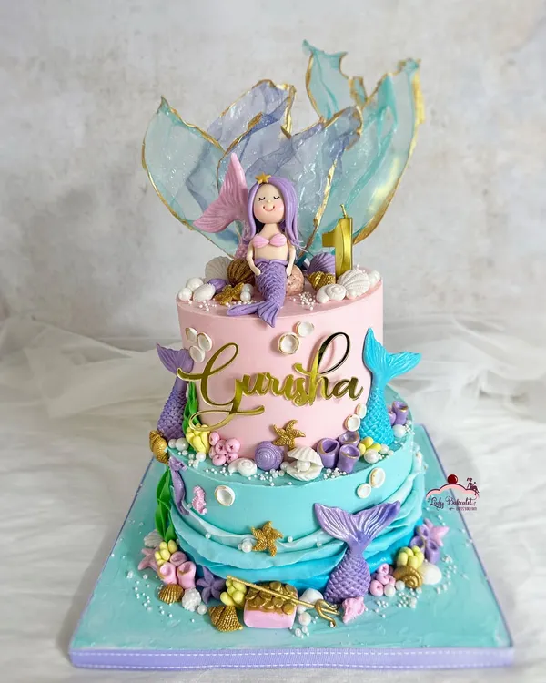 Make waves with this dreamy, two-tier mermaid theme cake. It features beautiful pastel colors, shimmering rice paper sails, and lots of underwater details.