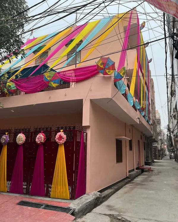 For this home wedding event, I transformed the entire house front with vibrant drapes in yellow, pink, and blue, along with decorative umbrellas and floral bunches on the gate.