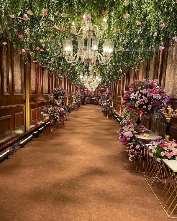 I designed this grand entrance to be an experience in itself. A long passage with rich, wood-paneled walls was transformed by a ceiling overflowing with fresh greenery and thousands of pink flowers, leading guests into a floral wonderland.