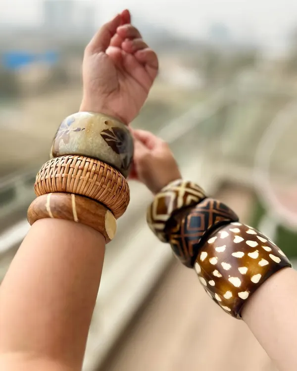 Stacking bangles is one of my favorite ways to accessorize. Here, I've mixed different wooden and resin bangles with various prints and textures to create a bohemian, Y2K-inspired look. It's all about playful layering.