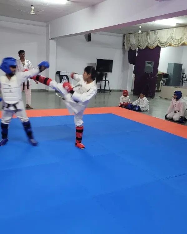 A student executes a high mawashi geri (roundhouse kick) during a kumite practice match. We focus on developing powerful and accurate kicking techniques for competition.